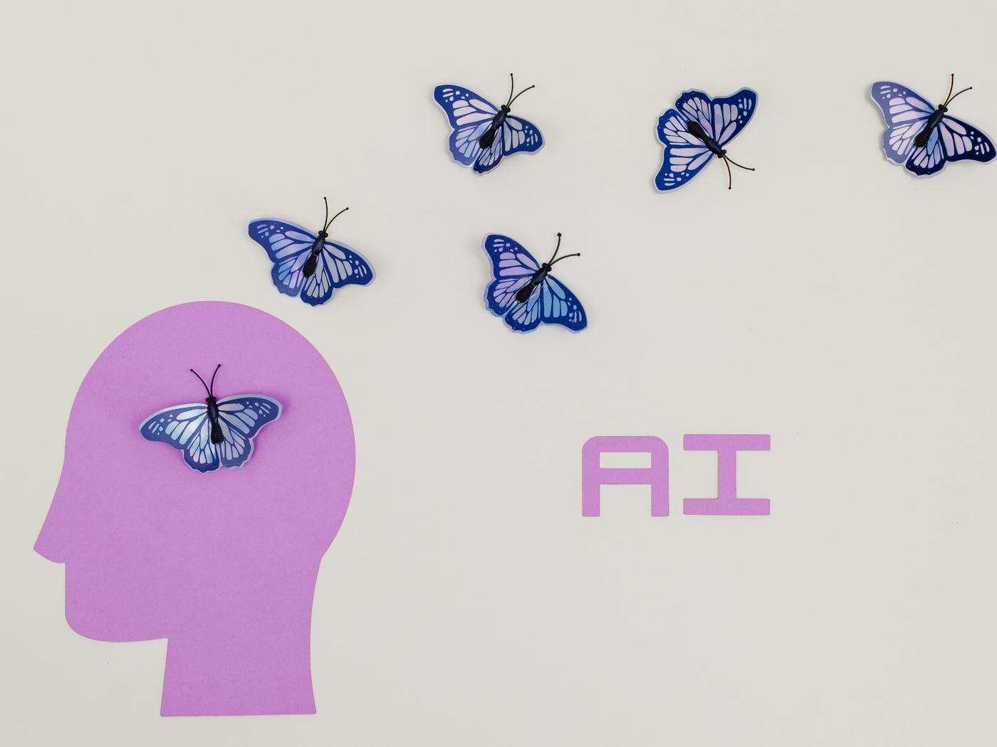 A paper cut-out head with butterflies and the letters A I