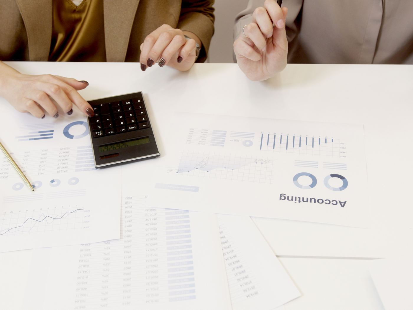 Printed accounts and charts being reviewed with a calculator
